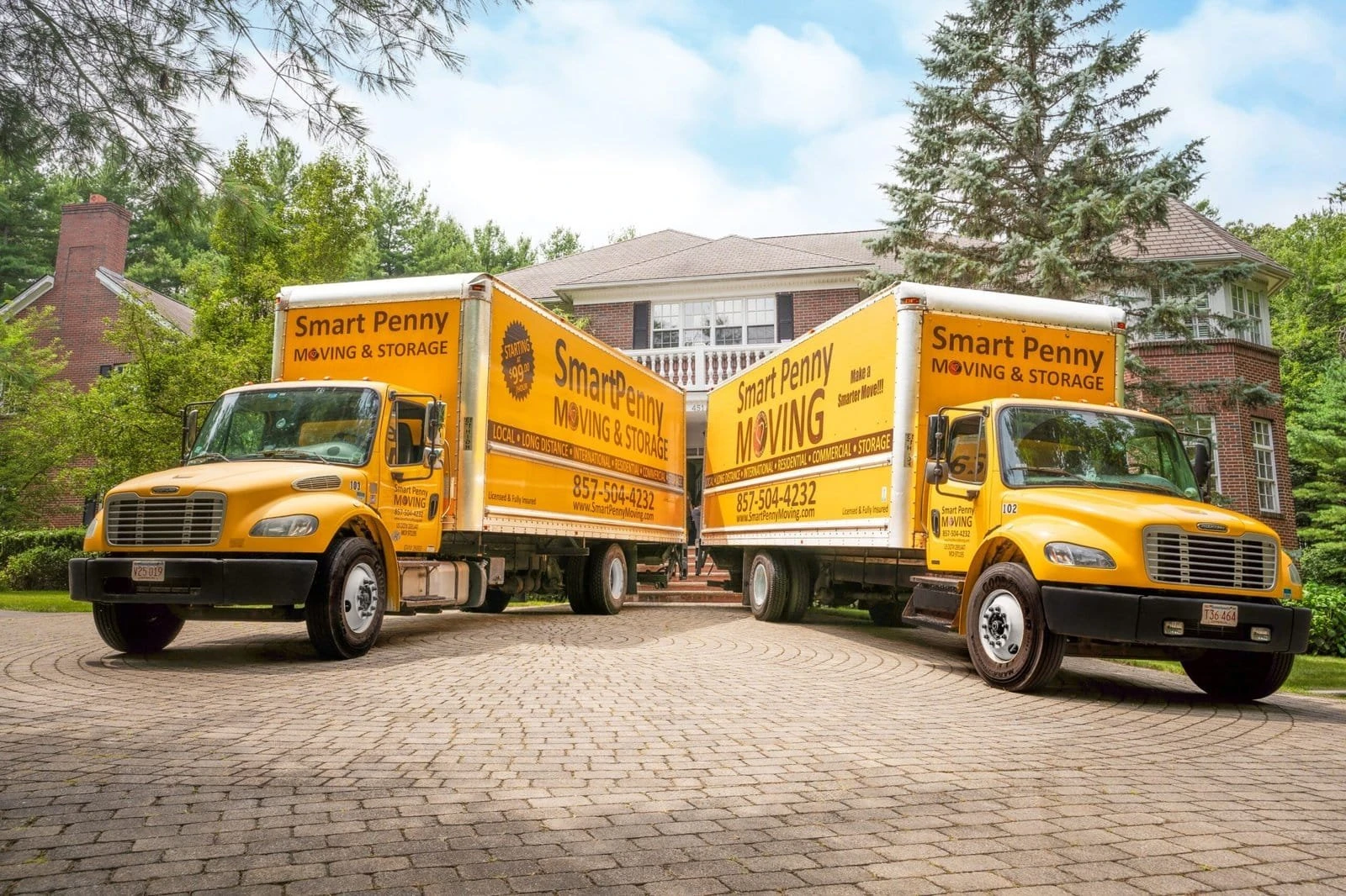 Two Smart Penny Moving trucks parked in front of a house